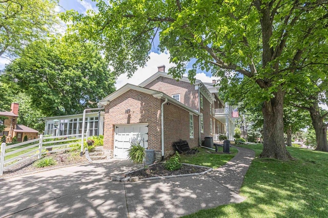 150 Rountree Ave, Platteville, WI 53818 - view of property exterior with brick siding, an attached garage, central air condition unit, driveway, and a chimney