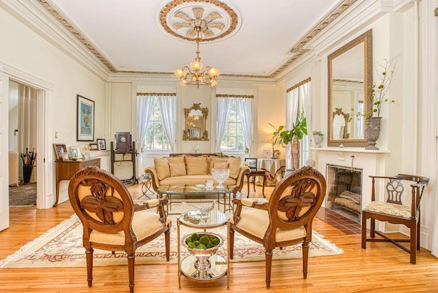 150 Rountree Ave, Platteville, WI 53818 - living area with crown molding, light wood-type flooring, a chandelier, and a fireplace with flush hearth