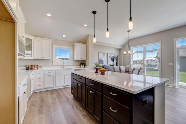 1320 Prairie Creek Cir Unit 2, Oconomowoc, WI 53066 - kitchen featuring white cabinetry, light countertops, light wood-style floors, a kitchen island, and a chandelier