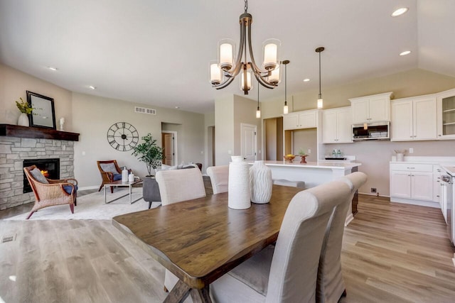 1320 Prairie Creek Cir Unit 2, Oconomowoc, WI 53066 - dining room featuring light wood-style flooring, a chandelier, a fireplace, recessed lighting, and lofted ceiling