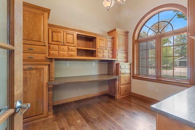 448 Harvest Rd, Green Bay, WI 54302 - unfurnished office featuring built in desk, dark wood-type flooring, and baseboards