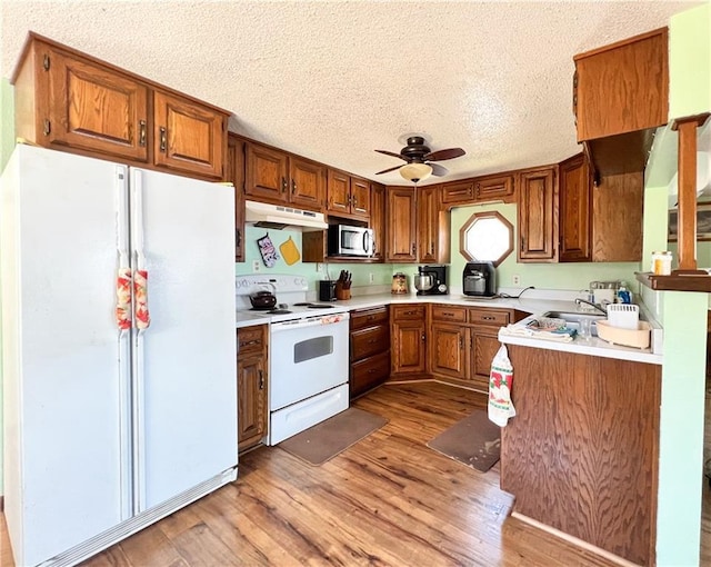 999 Mcgill Point Rd, Weyerhaeuser, WI 54895 - kitchen with white appliances, under cabinet range hood, brown cabinets, a ceiling fan, and a textured ceiling