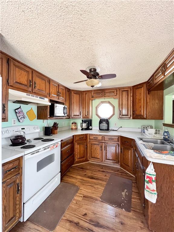 999 Mcgill Point Rd, Weyerhaeuser, WI 54895 - kitchen with electric range, under cabinet range hood, wood finished floors, stainless steel microwave, and light countertops