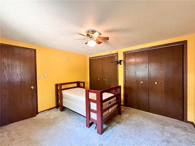 999 Mcgill Point Rd, Weyerhaeuser, WI 54895 - bedroom with multiple closets, light colored carpet, a textured ceiling, and a ceiling fan