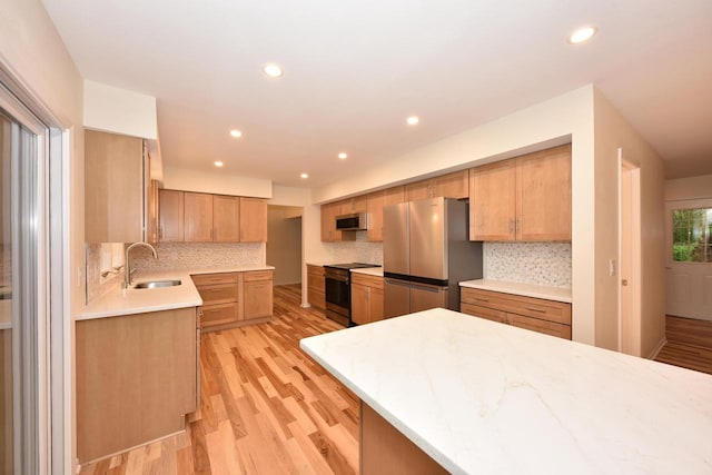 15710 Kata Dr, Elm Grove, WI 53122 - kitchen featuring appliances with stainless steel finishes, a sink, light wood-style floors, light countertops, and tasteful backsplash