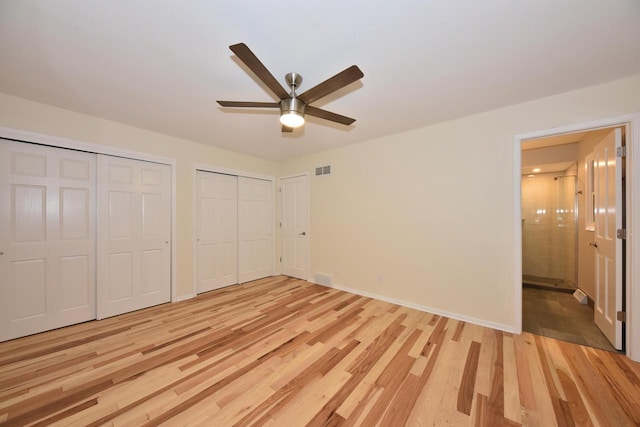 15710 Kata Dr, Elm Grove, WI 53122 - unfurnished bedroom featuring multiple closets, light wood-style floors, baseboards, ensuite bathroom, and a ceiling fan