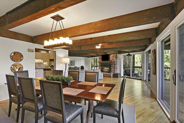 940 Alpine Dr Unit 01, Fontana, WI 53125 - dining space with beamed ceiling, light wood-style flooring, a brick fireplace, a ceiling fan, and baseboards