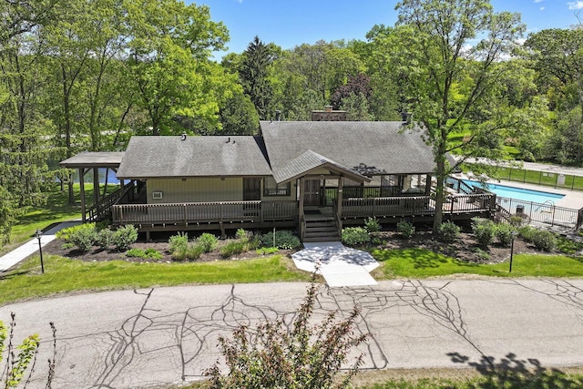 940 Alpine Dr Unit 01, Fontana, WI 53125 - view of front of home with a shingled roof, a community pool, a wooden deck, and a chimney