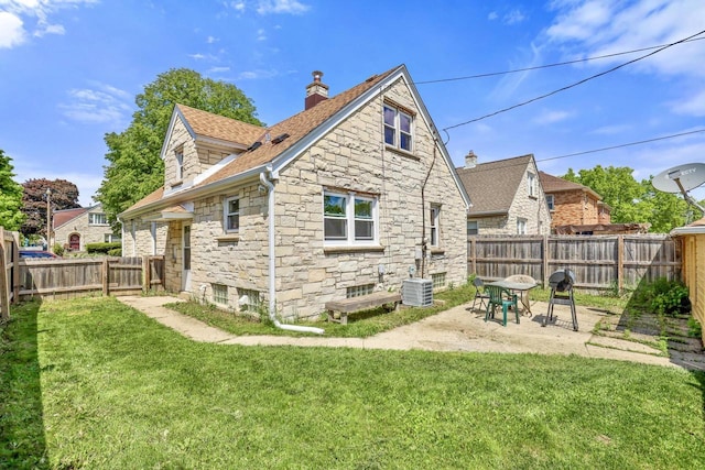 3612 N 57th St, Milwaukee, WI 53216 - back of property featuring stone siding, a chimney, cooling unit, roof with shingles, and a patio