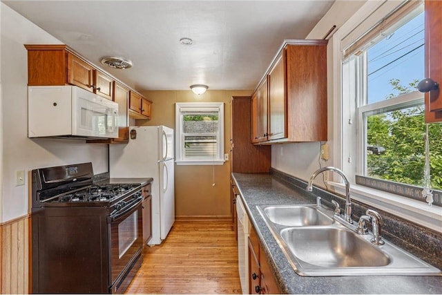 201 5th St, Centuria, WI 54824 - kitchen featuring white appliances, a sink, dark countertops, light wood-style floors, and brown cabinets