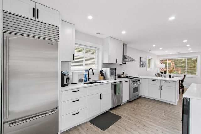 539 Highland Rd, Williams Bay, WI 53191 - kitchen featuring high quality appliances, a sink, a peninsula, wall chimney exhaust hood, and light countertops