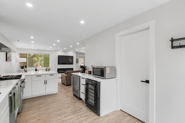 539 Highland Rd, Williams Bay, WI 53191 - kitchen with beverage cooler, stainless steel appliances, light wood finished floors, recessed lighting, and white cabinetry
