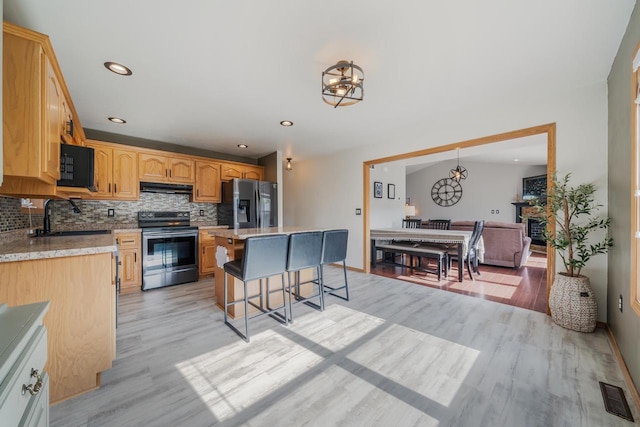 2759 Hamilton St, Oshkosh, WI 54901 - kitchen with stainless steel appliances, under cabinet range hood, a chandelier, a breakfast bar, and recessed lighting