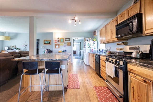 1843 190th St, Centuria, WI 54824 - kitchen featuring black appliances, dark countertops, a breakfast bar area, light wood-style floors, and open floor plan