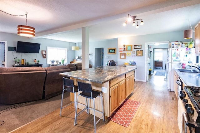 1843 190th St, Centuria, WI 54824 - kitchen with stainless steel range with gas cooktop, a sink, light wood-type flooring, and a kitchen bar