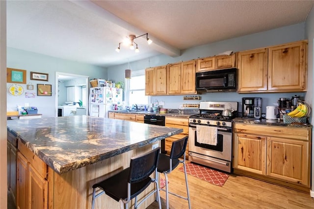1843 190th St, Centuria, WI 54824 - kitchen featuring black appliances, dark countertops, light wood-style floors, a breakfast bar, and a textured ceiling