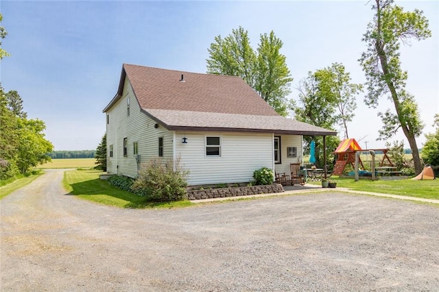 1843 190th St, Centuria, WI 54824 - view of front facade featuring driveway, a playground, roof with shingles, and a front yard