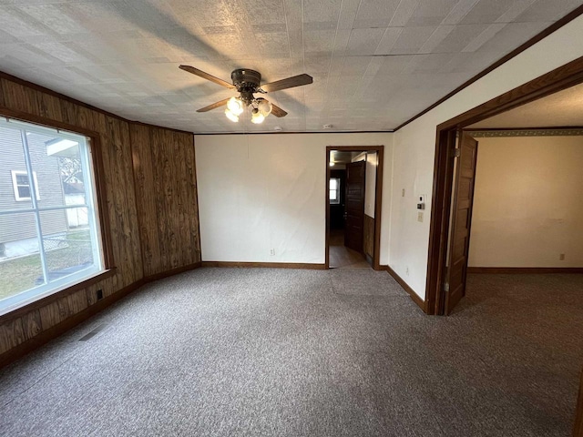 856 8th St, Beloit, WI 53511 - spare room featuring baseboards, a ceiling fan, wooden walls, carpet, and ornamental molding