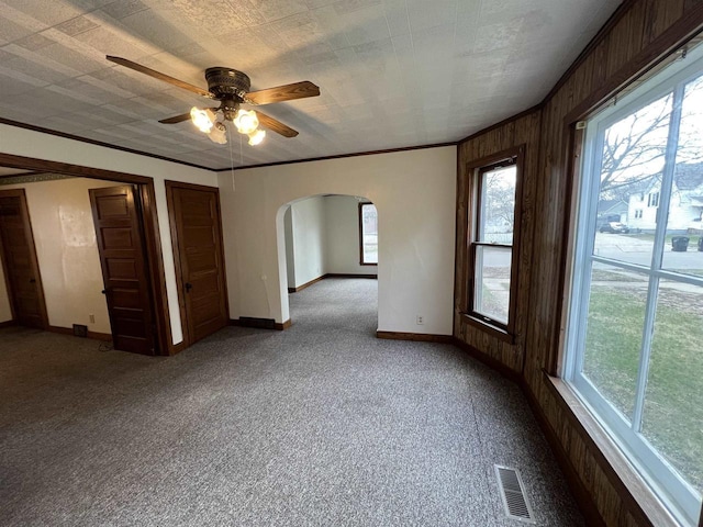 856 8th St, Beloit, WI 53511 - spare room featuring arched walkways, a ceiling fan, baseboards, carpet, and wood walls
