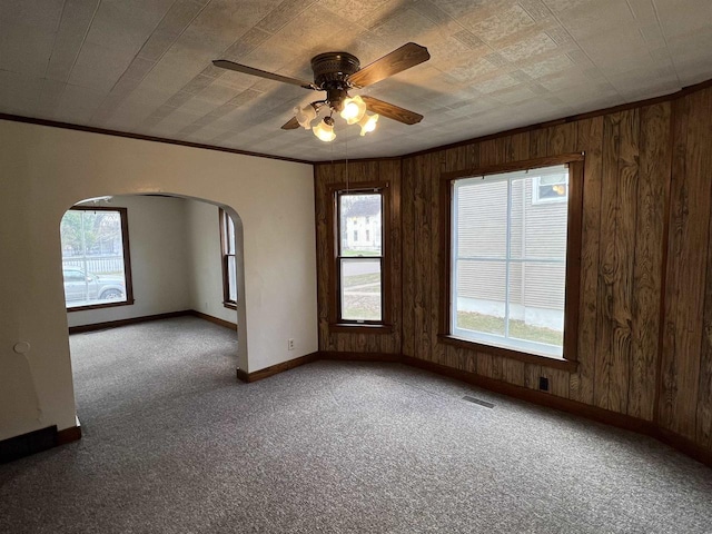 856 8th St, Beloit, WI 53511 - carpeted empty room featuring baseboards, arched walkways, healthy amount of natural light, wooden walls, and crown molding