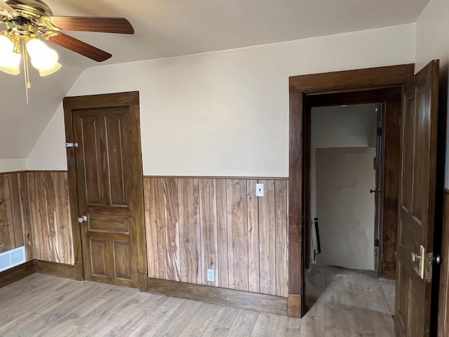 856 8th St, Beloit, WI 53511 - empty room featuring a ceiling fan, wainscoting, light wood-style flooring, wood walls, and vaulted ceiling