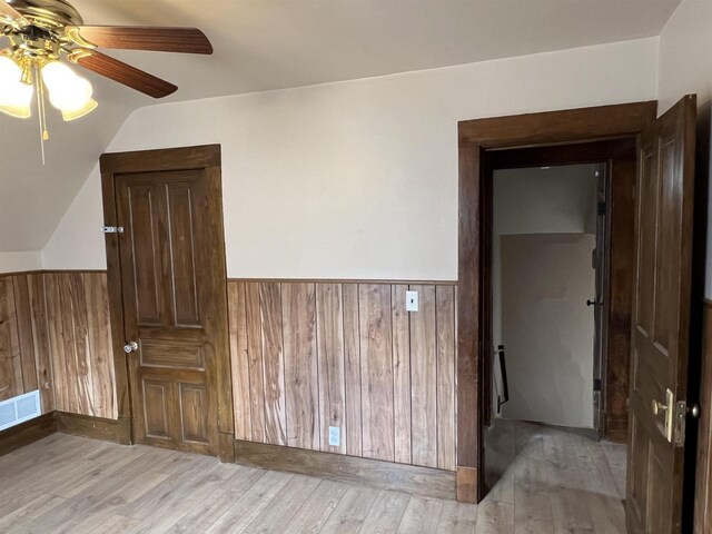 856 8th St, Beloit, WI 53511 - empty room featuring a ceiling fan, wainscoting, light wood-style flooring, wood walls, and vaulted ceiling