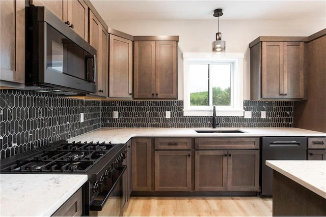 415 Moelter Ln, Hudson, WI 54016 - kitchen featuring stainless steel appliances, a sink, backsplash, decorative light fixtures, and light wood-type flooring