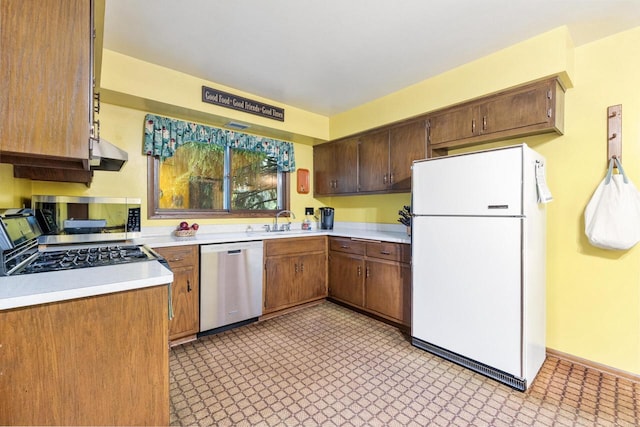 1001 W Fairfield Ct, Glendale, WI 53217 - kitchen featuring appliances with stainless steel finishes, light countertops, under cabinet range hood, a sink, and light flooring