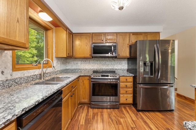 9432 James Ave, Sparta, WI 54656 - kitchen with appliances with stainless steel finishes, a sink, wood finished floors, backsplash, and light stone countertops