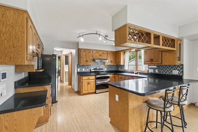 S38W32310 Green Briar Rd, Waukesha, WI 53189 - kitchen featuring double oven range, a peninsula, under cabinet range hood, light wood-type flooring, and backsplash