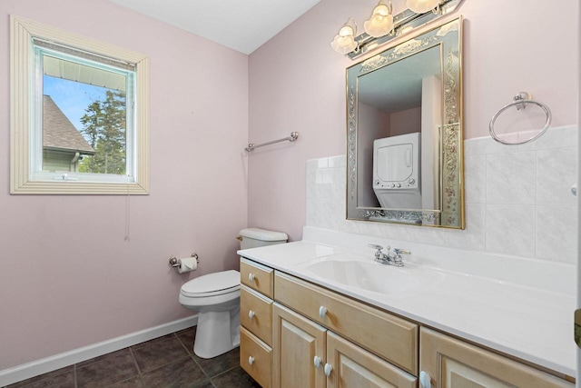 1305 Mahogany Run, Two Rivers, WI 54241 - bathroom with stacked washing machine and dryer, vanity, toilet, tile patterned flooring, and baseboards