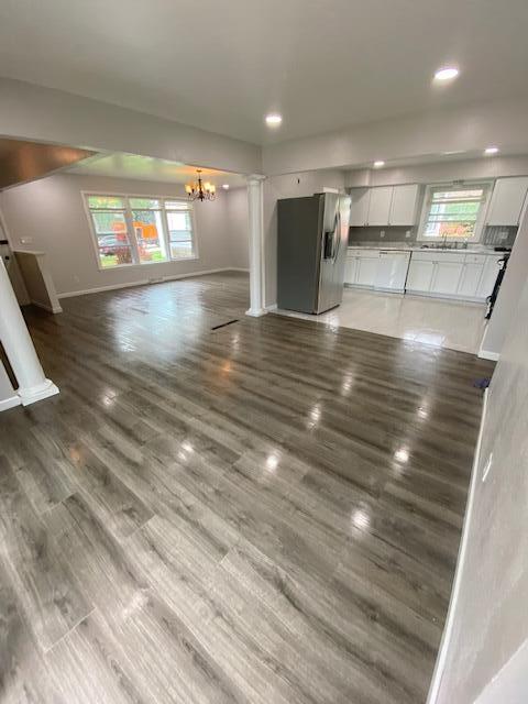 4265 S Nicholson Ave, Saint Francis, WI 53235 - unfurnished living room with a chandelier, baseboards, wood finished floors, recessed lighting, and ornate columns