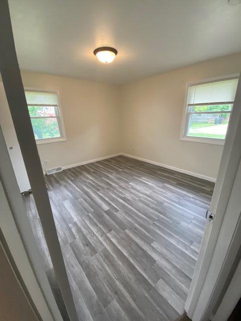 4265 S Nicholson Ave, Saint Francis, WI 53235 - empty room featuring healthy amount of natural light, baseboards, and dark wood-style floors