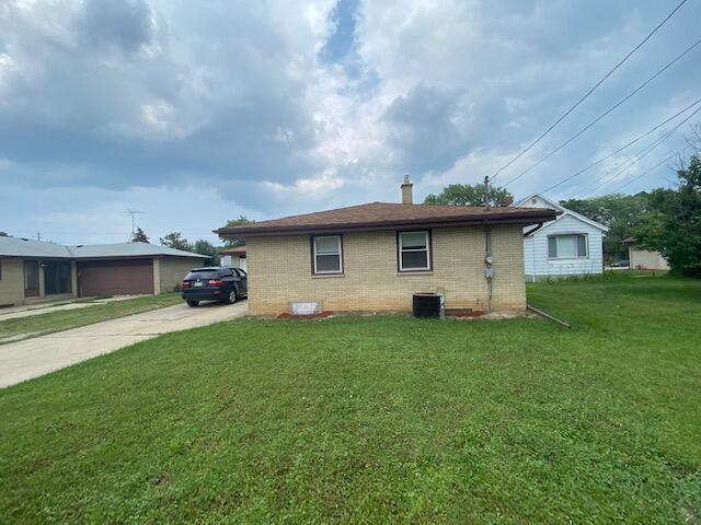 4265 S Nicholson Ave, Saint Francis, WI 53235 - view of side of property with a chimney, brick siding, a lawn, central AC unit, and driveway