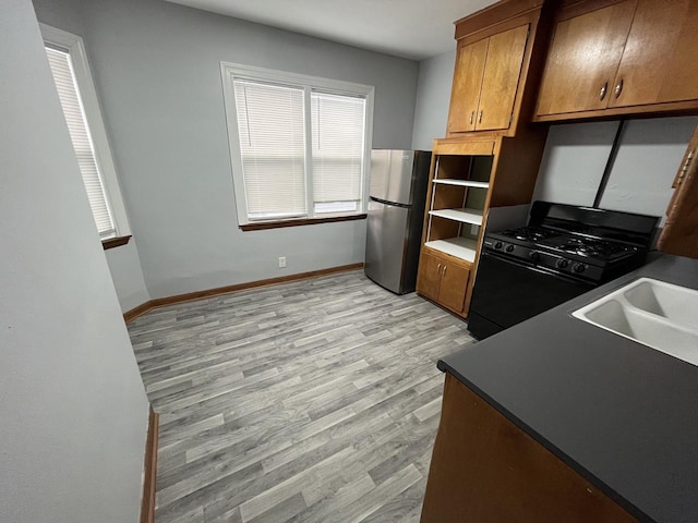 909 College Ave, Racine, WI 53403 - kitchen featuring black gas range, freestanding refrigerator, brown cabinetry, and light wood finished floors