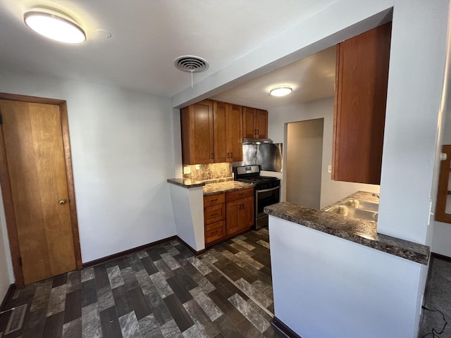 909 College Ave, Racine, WI 53403 - kitchen featuring gas stove, backsplash, brown cabinets, dark wood-style flooring, and dark countertops
