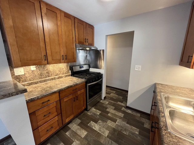 909 College Ave, Racine, WI 53403 - kitchen featuring stainless steel range with gas stovetop, under cabinet range hood, decorative backsplash, and brown cabinetry