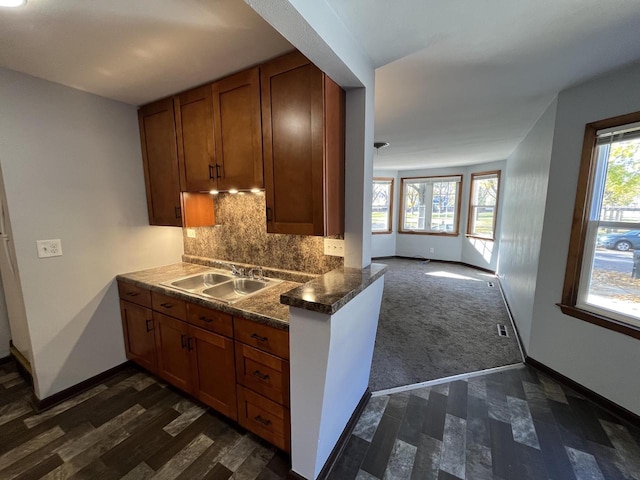 909 College Ave, Racine, WI 53403 - kitchen with brown cabinetry, dark wood-style floors, backsplash, and dark countertops