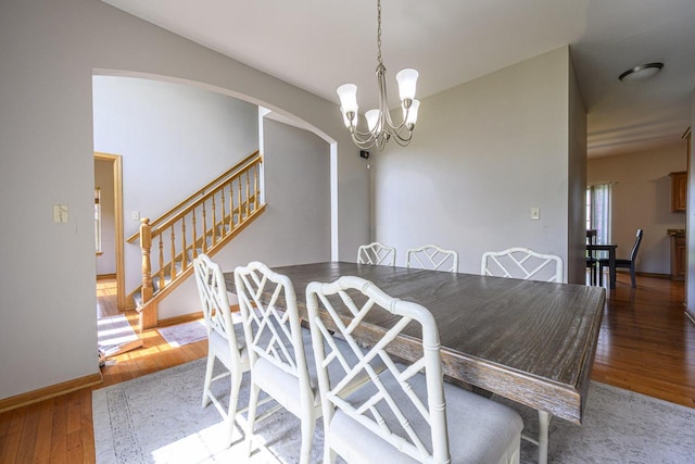 5278 W Highlands Ct, Franklin, WI 53132 - dining room featuring a chandelier, wood finished floors, arched walkways, stairway, and baseboards