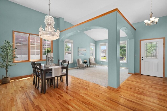 4017 Sandhill Dr, Janesville, WI 53546 - dining space featuring a chandelier, vaulted ceiling, arched walkways, hardwood / wood-style floors, and plenty of natural light