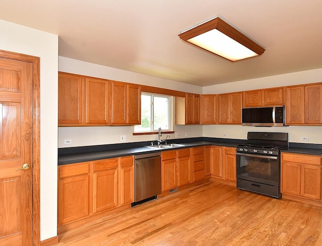 6023 241st Ave, Salem, WI 53168 - kitchen with appliances with stainless steel finishes, a sink, dark countertops, light wood-style floors, and brown cabinets