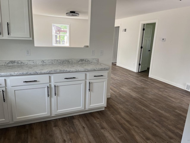 524 Charles St, Reedsburg, WI 53959 - kitchen featuring white cabinetry, dark wood-style flooring, and baseboards