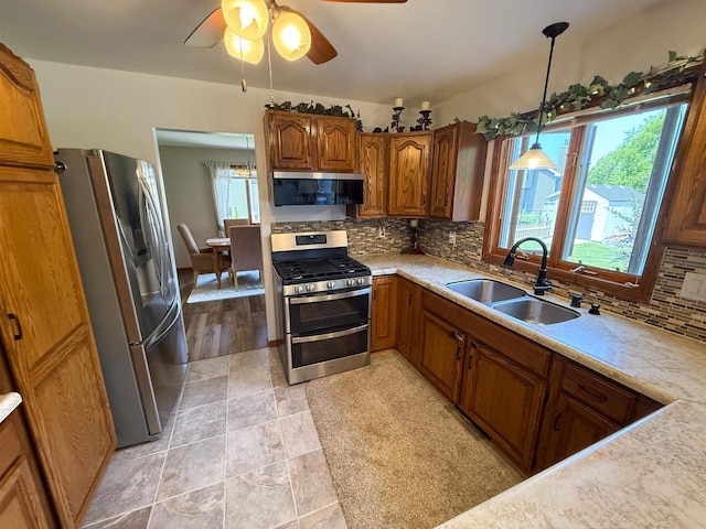 1053 Eastman Ln, Fond Du Lac, WI 54935 - kitchen with stainless steel appliances, a sink, backsplash, brown cabinets, and light countertops