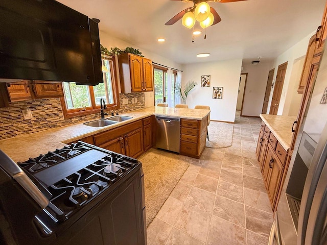 1053 Eastman Ln, Fond Du Lac, WI 54935 - kitchen with dishwasher, black range with gas stovetop, a sink, brown cabinets, and a peninsula