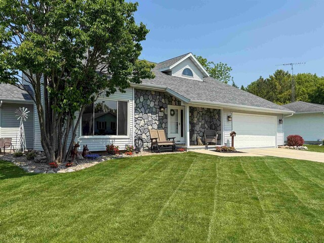 1053 Eastman Ln, Fond Du Lac, WI 54935 - view of front of home featuring stone siding, a garage, a front lawn, and concrete driveway