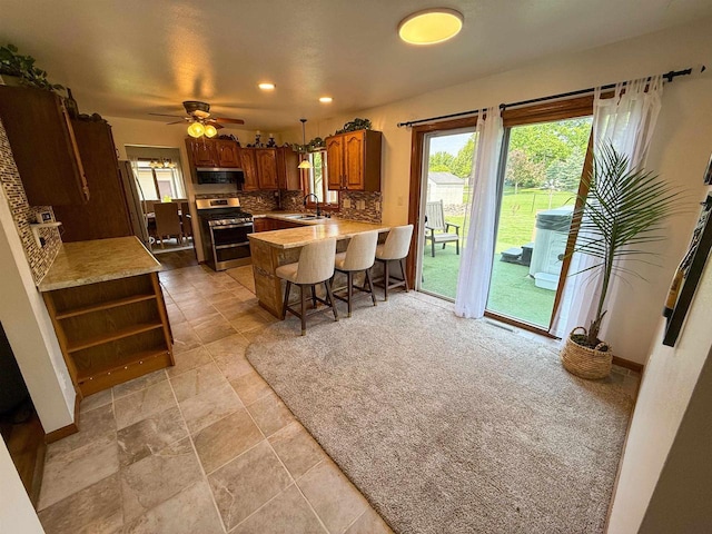 1053 Eastman Ln, Fond Du Lac, WI 54935 - kitchen featuring stainless steel gas range oven, a sink, decorative backsplash, a peninsula, and range hood