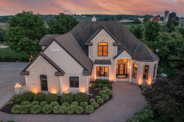 5015 Joshua Dr, West Bend, WI 53090 - french country inspired facade with brick siding, a shingled roof, and a standing seam roof