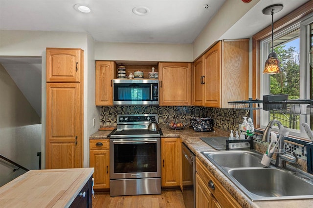 7320 Deer Rd, Wisconsin Rapids, WI 54494 - kitchen with stainless steel appliances, a sink, backsplash, light wood-style floors, and decorative light fixtures