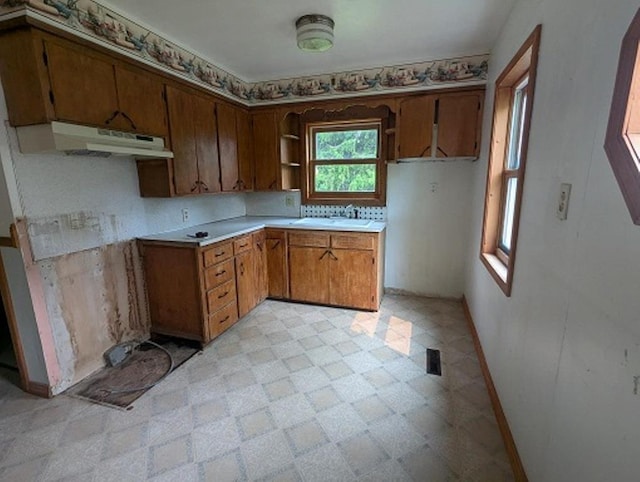 501 S Main St, Loyal, WI 54446 - kitchen with under cabinet range hood, light flooring, baseboards, brown cabinets, and light countertops
