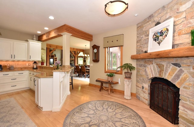 W395S3611 Hardscrabble Rd, Dousman, WI 53118 - kitchen featuring light wood-type flooring, white cabinetry, a stone fireplace, a peninsula, and recessed lighting